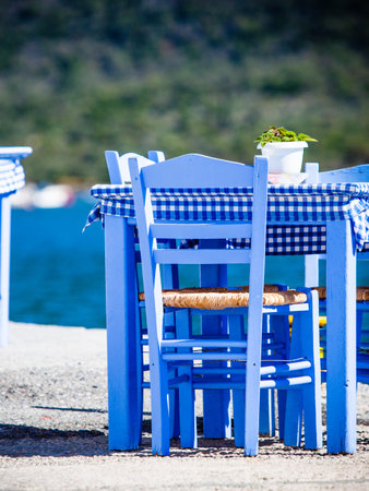 Seaside blue table and chairs open cafe outdoor restaurant in Greece on sea shore. Summer vacation on resort.の写真素材