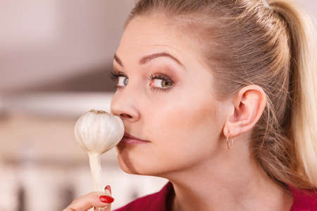 Woman holding healthy herb, two fresh natural garlic smelling it. Healthy eating and dieting concept.の写真素材