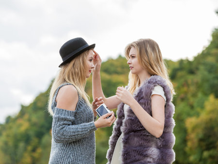 Behind the scenes of photo shoot. Two females friends having fun during outdoor photo session. Women...