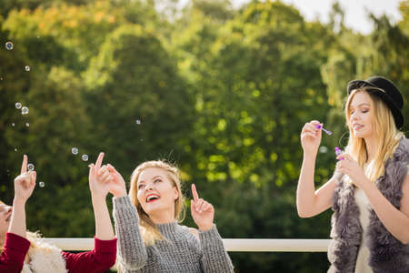 Vacations joy, friendship concept. Women friends having fun blowing soap bubbles outdoor.の写真素材
