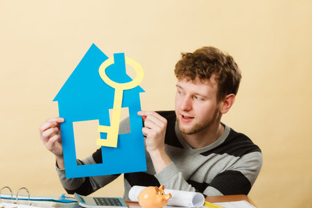 Dream about stabilization and family. Young man with paper house and big key. Dreaming boy full of...