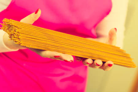 Woman holding long pasta macaroni ready to cook spaghetti. Healthy food concept.の写真素材