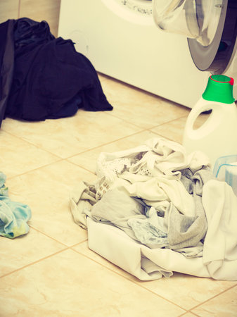 Washing powder detergent and measuring cup next to machine in bathroom. Household duties, clothes...