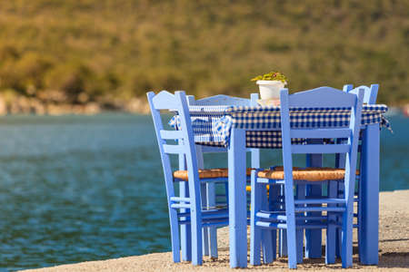 Seaside blue table and chairs open cafe outdoor restaurant in Greece on sea shore. Summer vacation on resort.の写真素材