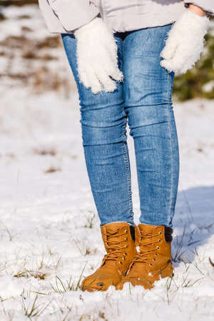 Unrecognizable woman wearing blue jeans and warm brown boots shoes. Winter snow footwear.の写真素材