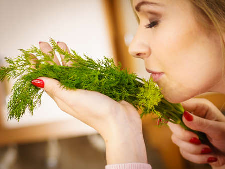 Young female holding herbs. Pretty woman having dill herb smelling it scent.の写真素材