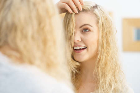 Happy woman having wet blonde hair. Positive clean female after taking a shower feeling clean and relaxed.の写真素材