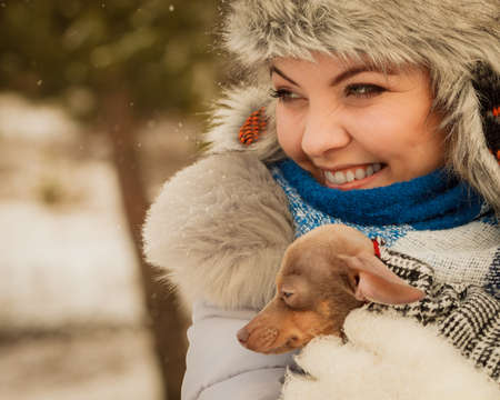 Young woman wrapped her best friend little dog in warm blanket scarf to warm him in cold snowy winter day. Animal protection save. Adoption conceptの写真素材