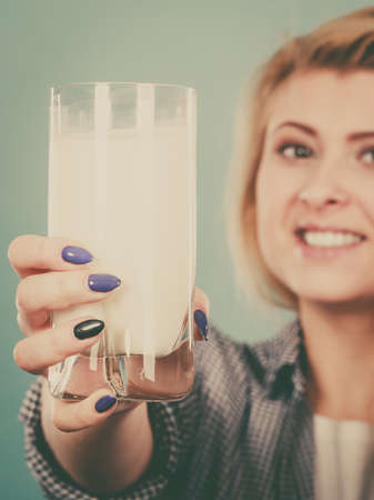 Healthy drinks, good nutrition, dairy products concept. Woman holding glass of milk showing thumb up gestureの写真素材