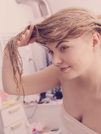 Happy woman having wet blonde hair. Positive clean female after taking a shower feeling clean and...