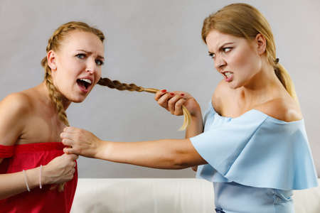 Two young pretty women being mad at each other having argue fight. Friendship rivaly and envy problems.の写真素材