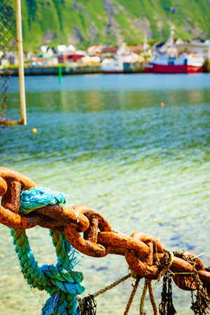 Rusty old metal chain links in port. Marine details. Bleik village in the background.の写真素材