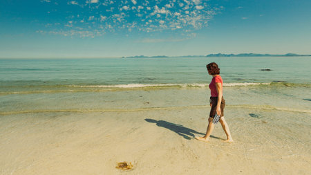Tourist woman relaxing walking on sea shore. Coast of Gimsoya island, Gimsoysand sandy beach in...
