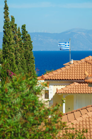 White blue state flag of Greece on roof of private estate, tourist house in seaside Mediterranean...