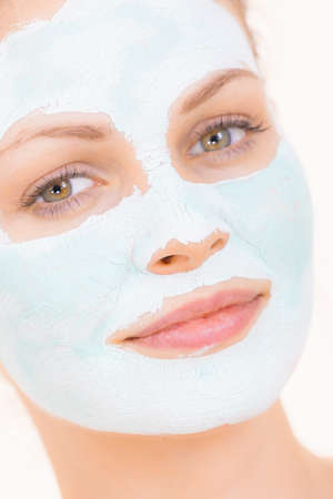 Young woman with white green mud mask on her face. Teen girl taking care of oily skin, cleaning the pores. Beauty treatment. Skincare.の写真素材