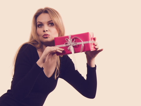 Cheerful girl holding present shaking pink gift box, trying to guess what is inside. Christmas...