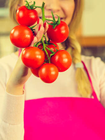 Close up of woman holding tomatoes on branch. Healthy lifestyle, dieting food, eating vegetables concept.の写真素材