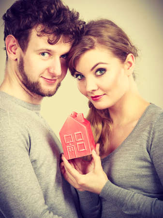 Property ownership family future finances mortgage bank concept. Youthful pair with house model. Young lady with man posing together with home symbol.の写真素材
