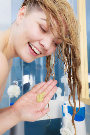 Happy woman having wet blonde hair. Positive female about to wash her hairdoの写真素材