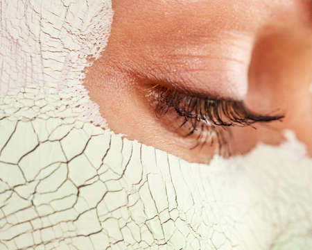 Close up woman with green white mud mask on face, detail view. Teen girl have dry cracked cosmetic on skin. Beauty treatment. Skincare.の写真素材