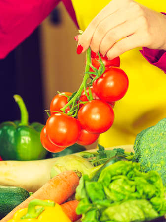 Woman picking tomatoes from healthy colorful vegetables on kitchen table. Dieting, vegetarian local fresh food, natural source of vitamins.の写真素材