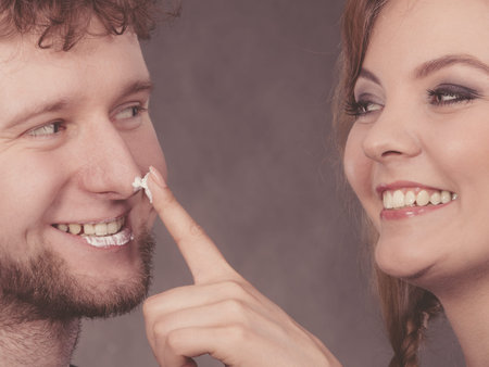 Beauty skin care health concept. Young couple fooling with cream. Man and woman having fun with...