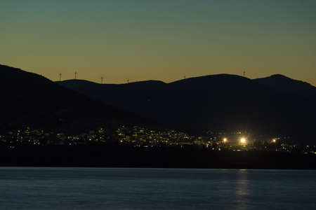 Night scene of Astros town with wind turbines on hills, Greece Peloponnese. Renewable eco energy concept.の写真素材
