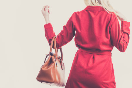 Fashionable pretty young woman wearing elegant casual red short dress and holding leather bag presenting stylish outfit.の写真素材