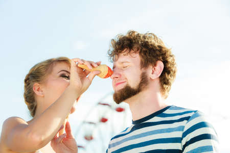 Summer holidays and happiness concept. Young couple eating ice cream outdoor in the cityの写真素材