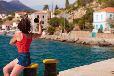 Tourism vacation and travel. Mature woman tourist in greek resort marina taking photo with camera....