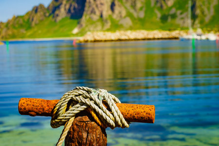 Harbor marina detail. Old rusty mooring bollard with rope. Bleik village, Andoya island, Vesteralen...