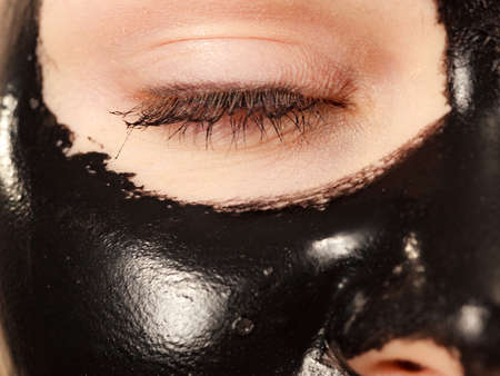 Young woman with carbo detox black peel-off mask on her face, detail view. Teen girl taking care of oily skin, cleaning the pores. Beauty treatment. Skincare.の写真素材