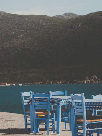 Seaside blue table and chairs open cafe outdoor restaurant in Greece on sea shore. Summer vacation on resort.の写真素材