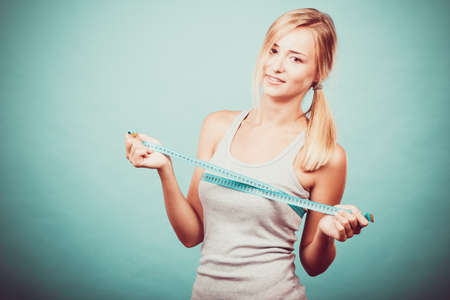 Fitness woman fit girl in sportswear with measure tape measuring her size chest breast on blueの写真素材
