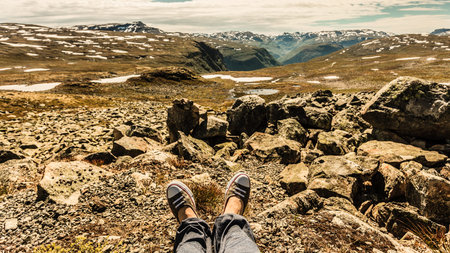 Female tourist relaxing on nature. Human legs and mountains landscape at summer in Norway. Tourism...