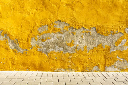 Old weathered painted yellow color peeling wall grunge backgroundの写真素材
