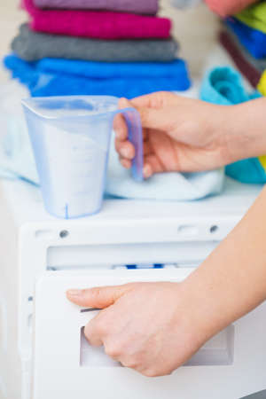 Washing powder detergent and measuring cup pouring into machine. Household duties, clothes laundry obejcts concept.の写真素材