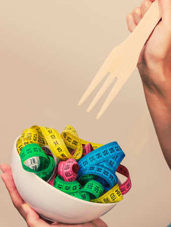 Diet, healthy eating, weight loss and slim body concept. Human hand holding bowl with many colorful...