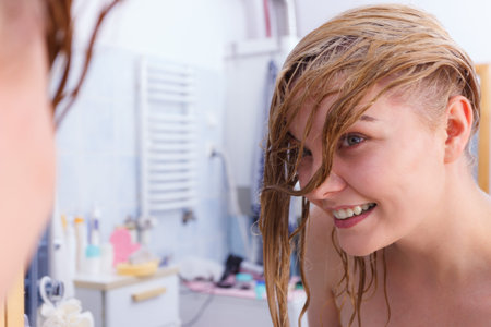 Happy woman having wet blonde hair. Positive clean female after taking a shower feeling clean and relaxed.の写真素材