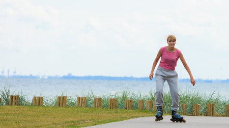 Holidays, active lifestyle freedom concept. Young fit woman on roller skates riding outdoors on sea...