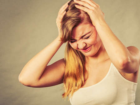 Health problem, stress and depression. Woman suffering from headache migraine pain. Stressed female holds her head with handsの写真素材