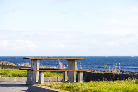 Picnic site rest stop area wooden chairs and table on norwegian sea shore. Holidays relaxation on trip. Scandinavia Europe.の写真素材