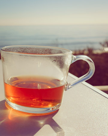 Big mug with tea drink outdoor, sunny day, ocean backgroundの写真素材