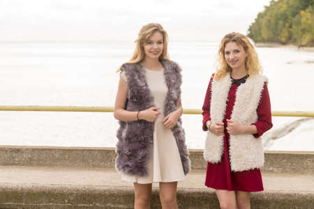 Two fashionable women wearing stylish outfits during warm autumnal weather spending their free time outdoorの写真素材