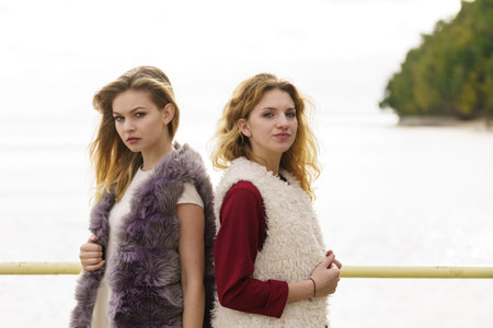 Two fashionable women wearing stylish outfits during warm autumnal weather spending their free time outdoorの写真素材