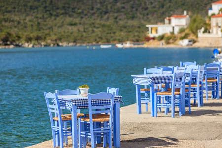 Seaside blue table and chairs open cafe outdoor restaurant in Greece on sea shore. Summer vacation on resort.の写真素材