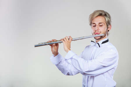 Flute music playing professional male flutist musician performer. Young elegant stylish man with instrumentの写真素材