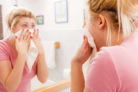 Woman with white towel wiping face after cleaning. Skin and complexion care concept.の写真素材