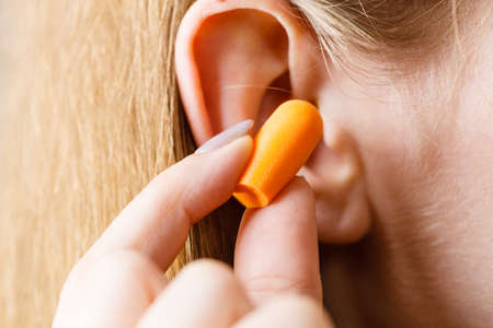 Woman putting ear plugs into her ears getting rid on noise in loud place.の写真素材