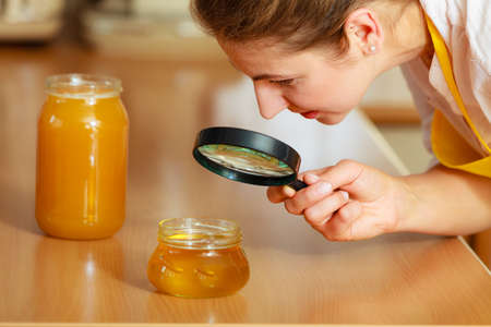 Mature woman female inspecting testing honey food with magnifying glass.の写真素材